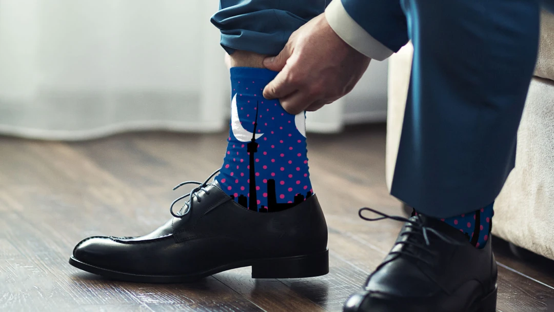 Businessman sporting jacquard knit socks creatively designed with the Toronto skyline for the multinational advertising and public relations company, Havas Media. A stylish example of custom branded merch for B2B business services from Brand Blvd.