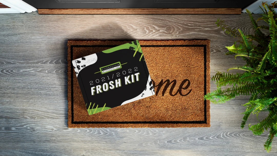 Conestoga College 2021/2022 mailer box sitting on a door mat outside of a front door.