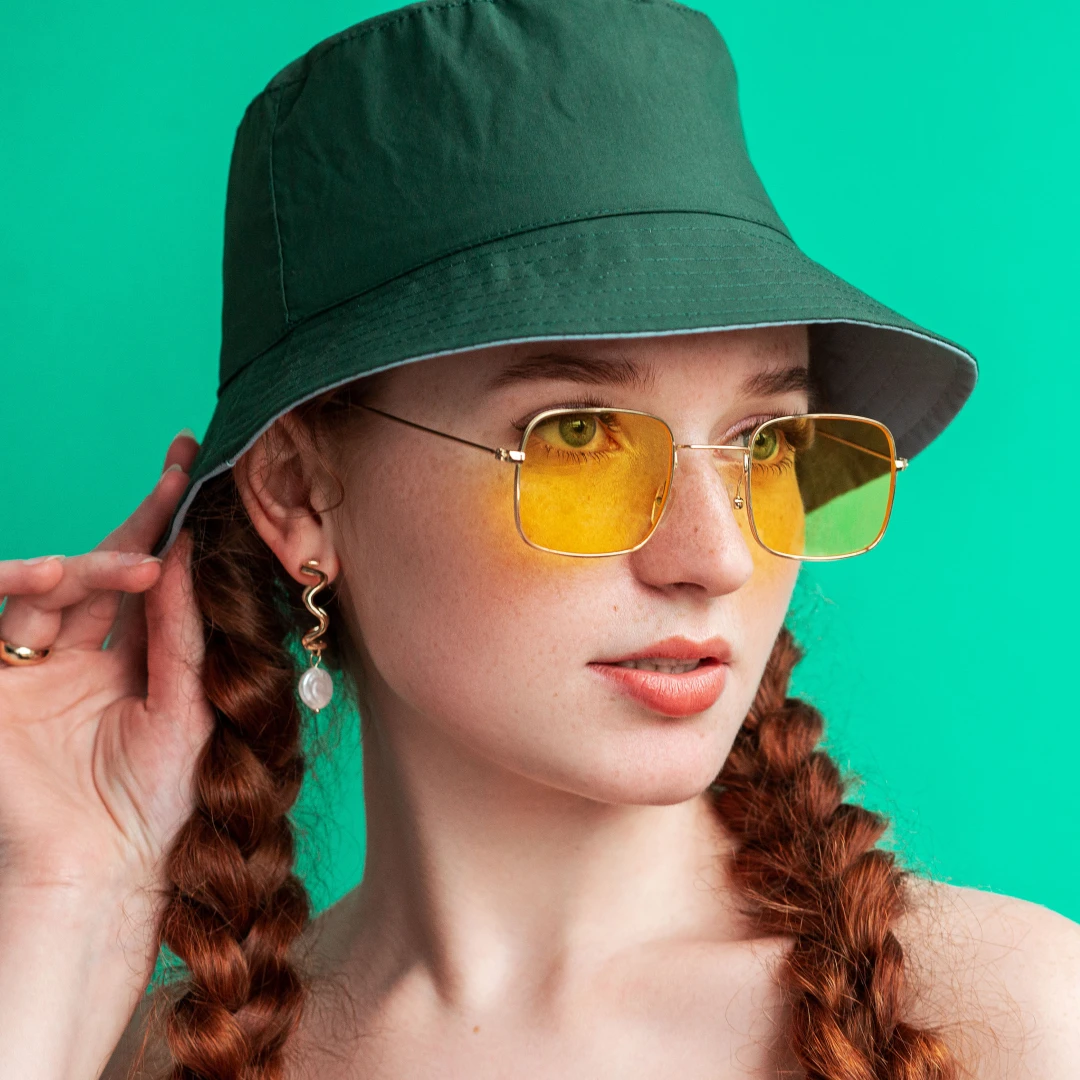 A young Gen Z woman wearing a bucket hat to match her trendsetting, 90s and 2000s fashion style.