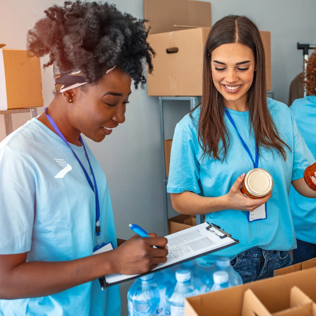 Volunteers showing the spirit of National Philanthropy Day by volunteering in their community with a food drive or fundraiser to showcase a culture of purpose and giving back while wearing branded t-shirts and logo merch from Brand Blvd.