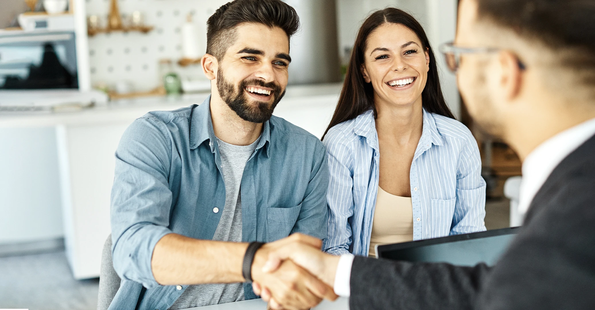 Recently acquired young adults meeting with a financial planner at a credit union, as they bond over trendy tech gadgets that the credit union uses as part of their onboarding marketing strategy.