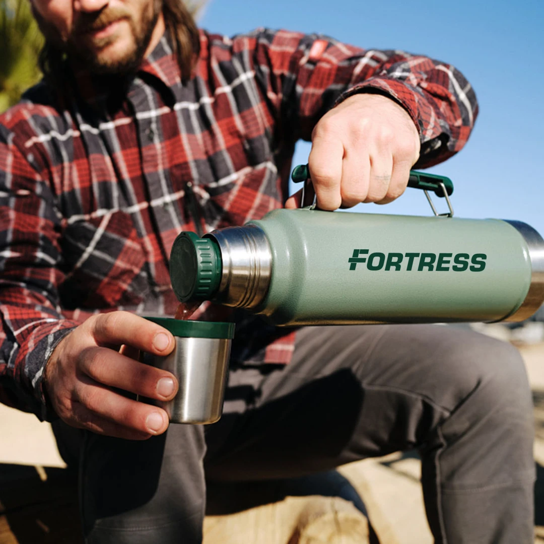 Man pouring a drink from a 48 oz Stanley Legendary Classic Bottle branded with a company logo - the ultimate branded merch for manufacturing and industrial companies. Premium thermos designed for durability and employee wellbeing. Stay refreshed with this 