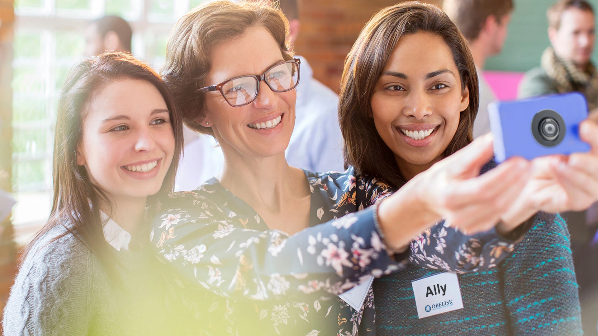 Three women from a member organization taking a selfie to capture the moment at a networking event with personalized membership gifts, name tags and custom branded merch from Brand Blvd.