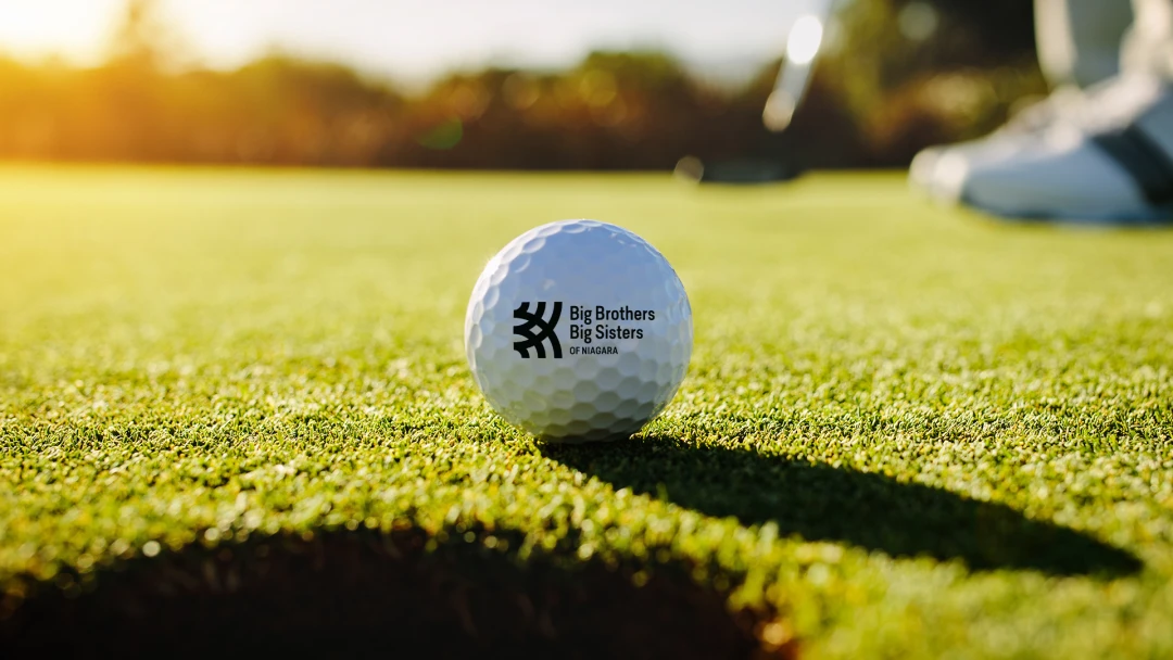 Golf ball with Big Brothers Big Sisters logo at a charity tournament. An example of sponsor-branded promotional products from Brand Blvd that support non-profits community impact and audience engagement.
