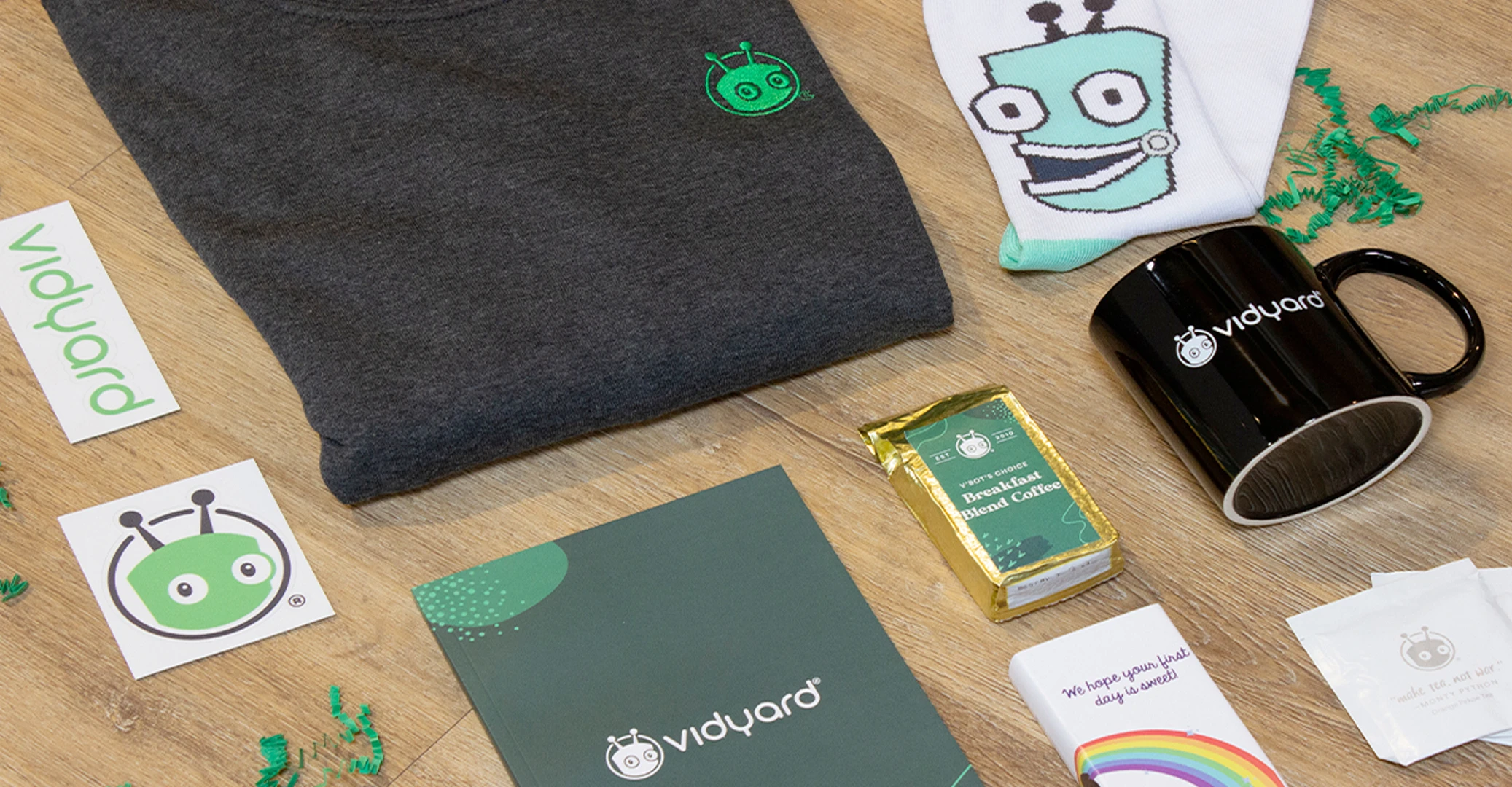 Onboarding Vidyard welcome kit for new hires includes a custom branded notebook, pen, sweater, mug, coffee, candy, and stickers; everything a new employee needs to feel welcome on the first day of work.