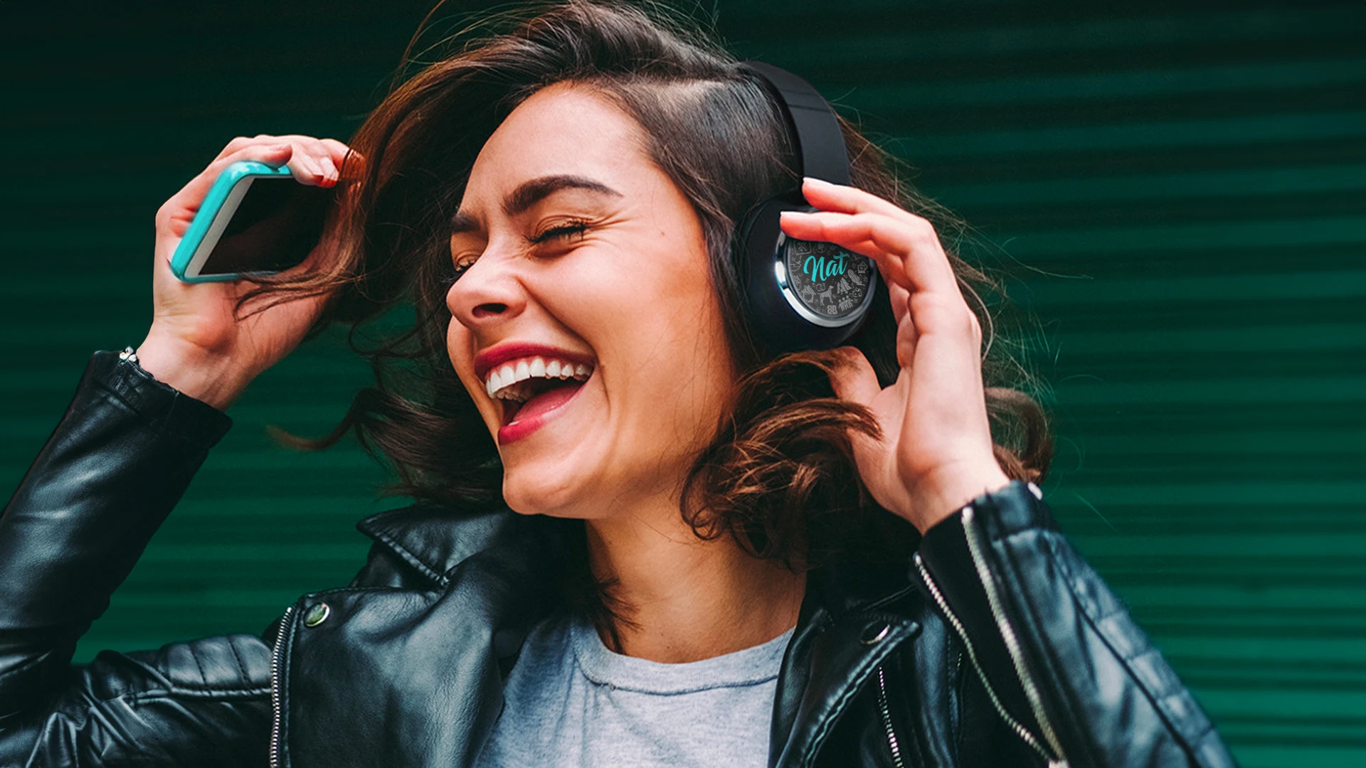 A happy woman wearing wireless headphones personalized with her name  – an example of a customized brand strategy experience with memorable keepsake merch from Brand Blvd.