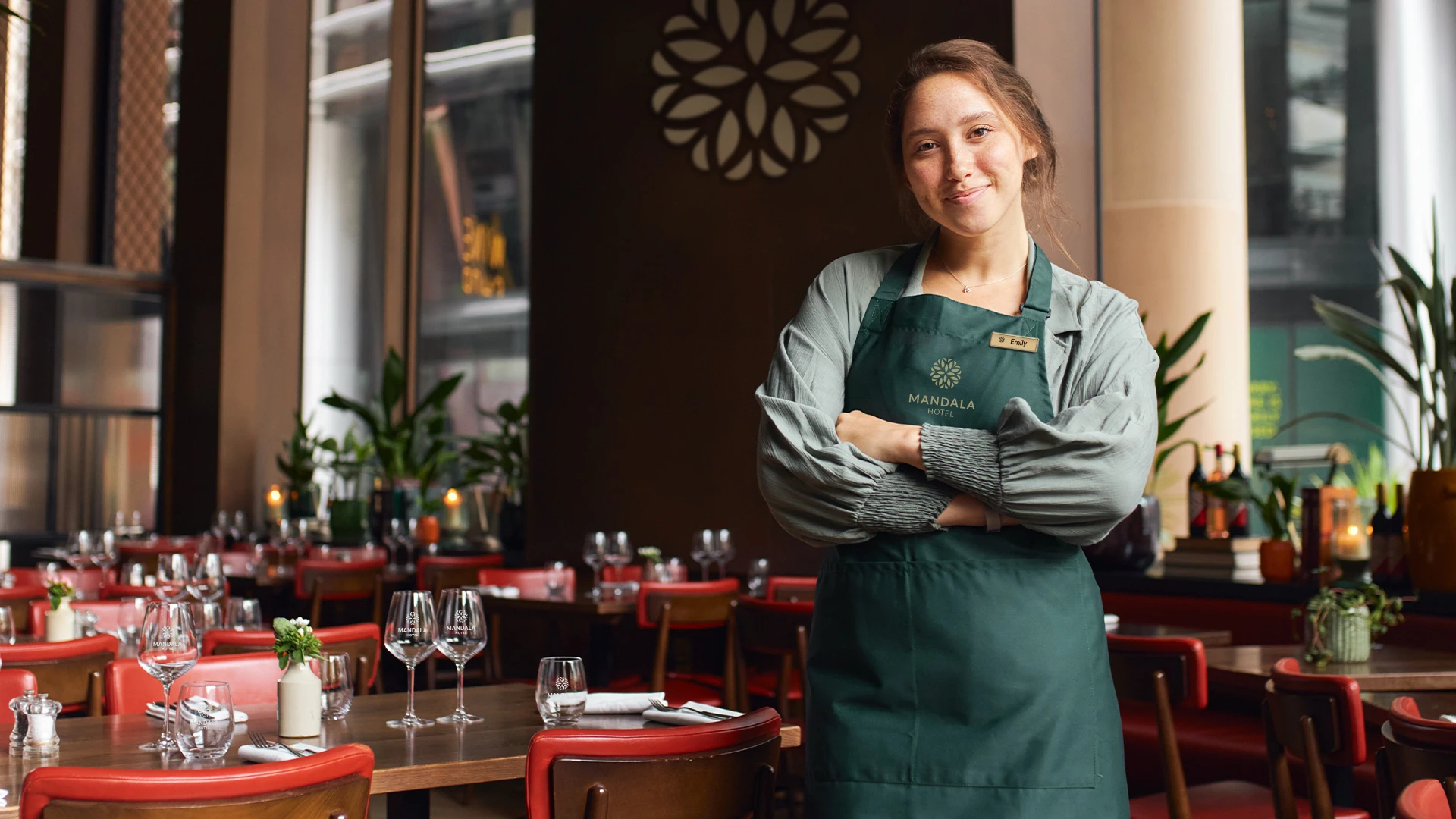 Luxury hotel restaurant employee wearing a branded apron and name tag, an example of branded merchandise for hospitality excellence and guest engagement from Brand Blvd.