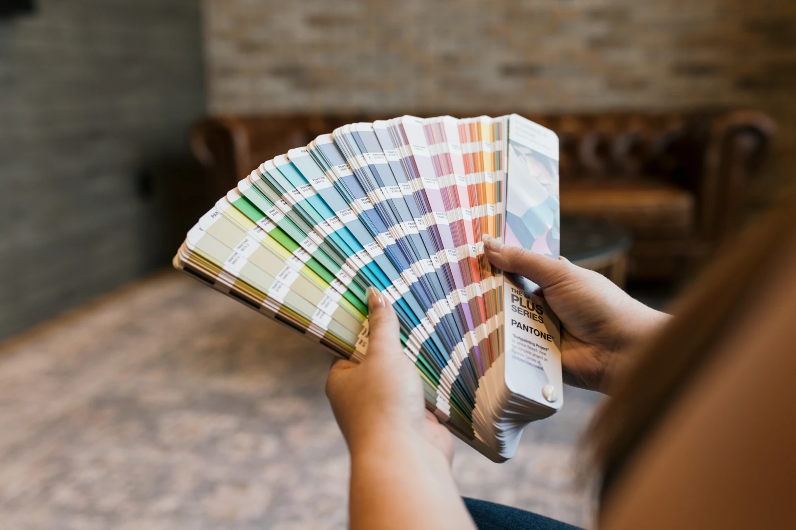 A photo of a Pantone colour swatch book fanned out in a persons hands. 