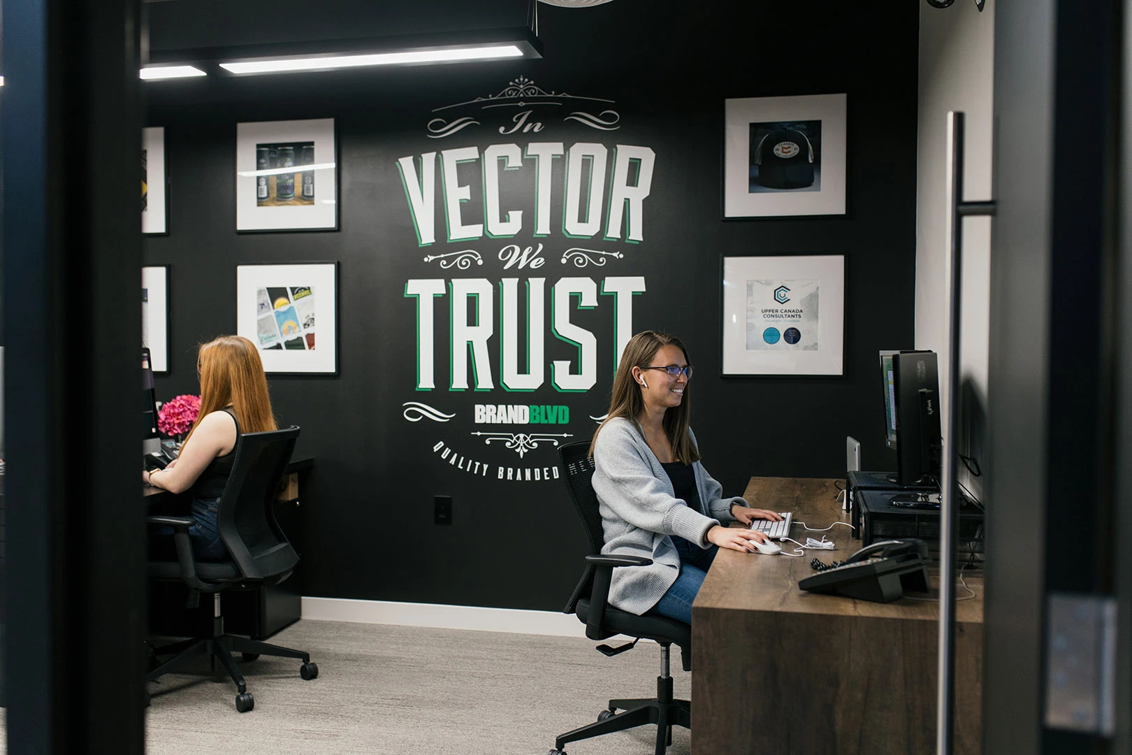A photo of 2 women working at a computer station in the Marketing department at Brand Blvd.