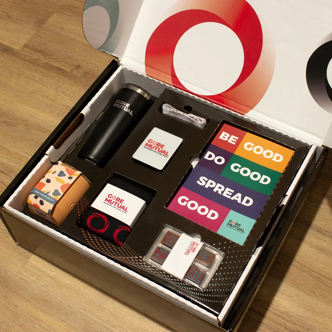 A photo of a Gore Mutual Insurance swag kit including a black tumbler, knitted socks, lanyard, power bank, notebook and seed sprouting kit.