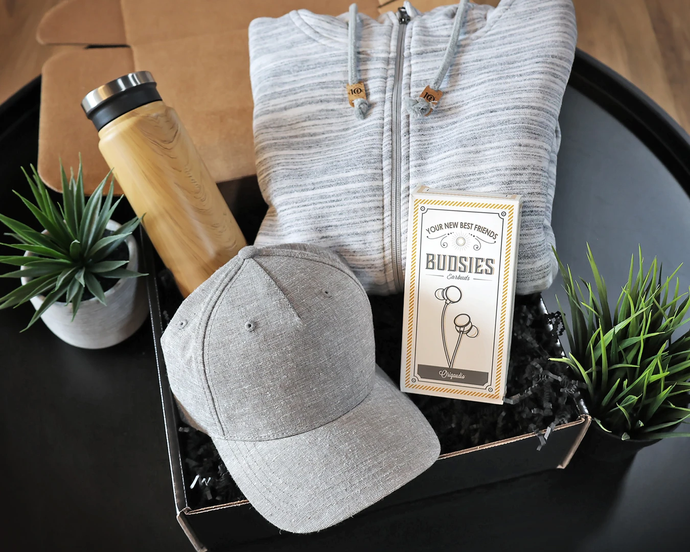 A photo of the Trendsetter curated swag kit which includes a full-zip sweater and ball cap from the coveted retail brand Tentree®, along with a complimentary wood grain print bottle and earbuds for the tunes.