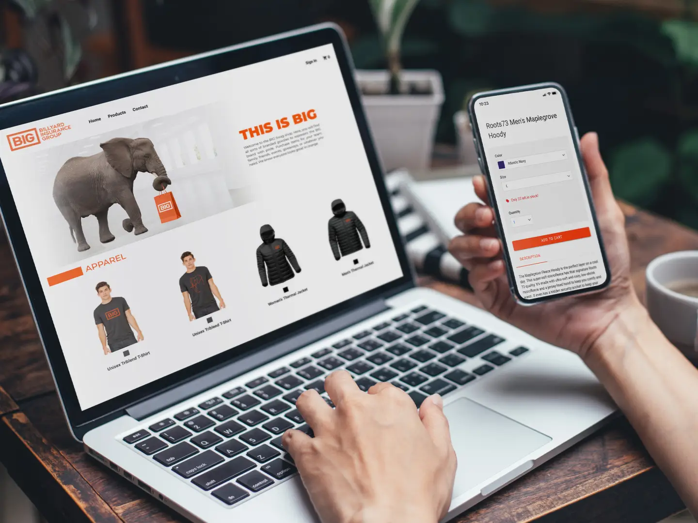 A photo of a person in front of a laptop browsing the Billyard Insurance Group online store home page, with a smartphone in their right hand viewing a product page.