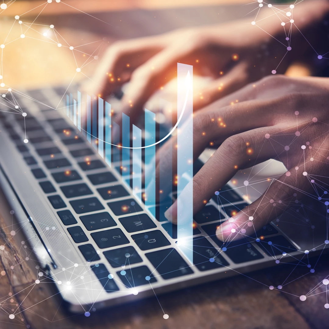 A photo of a pair of hands typing on a laptop keyboard with various translucent graphs and charts overlaid onto the image.